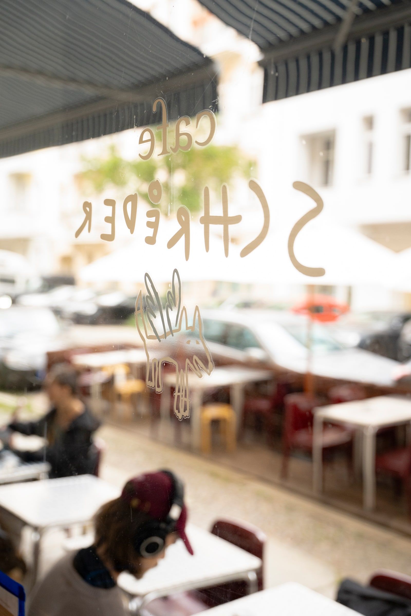 The Cafe Schroeder lettering and hand-drawn dog on the front window, looking out onto the terrace