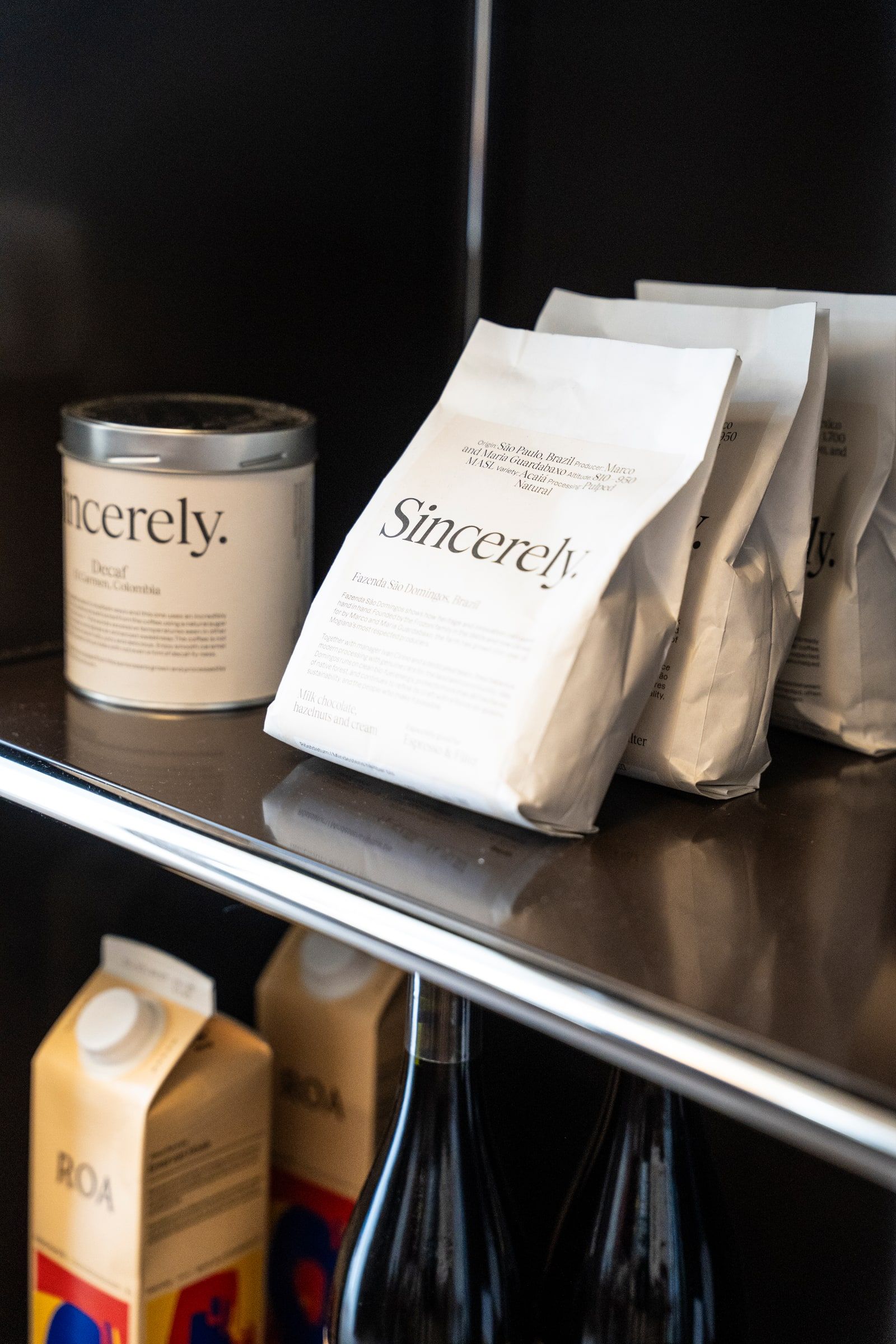 Bags and a tin of Sincerely coffee on a shelf, with cartons and bottles below
