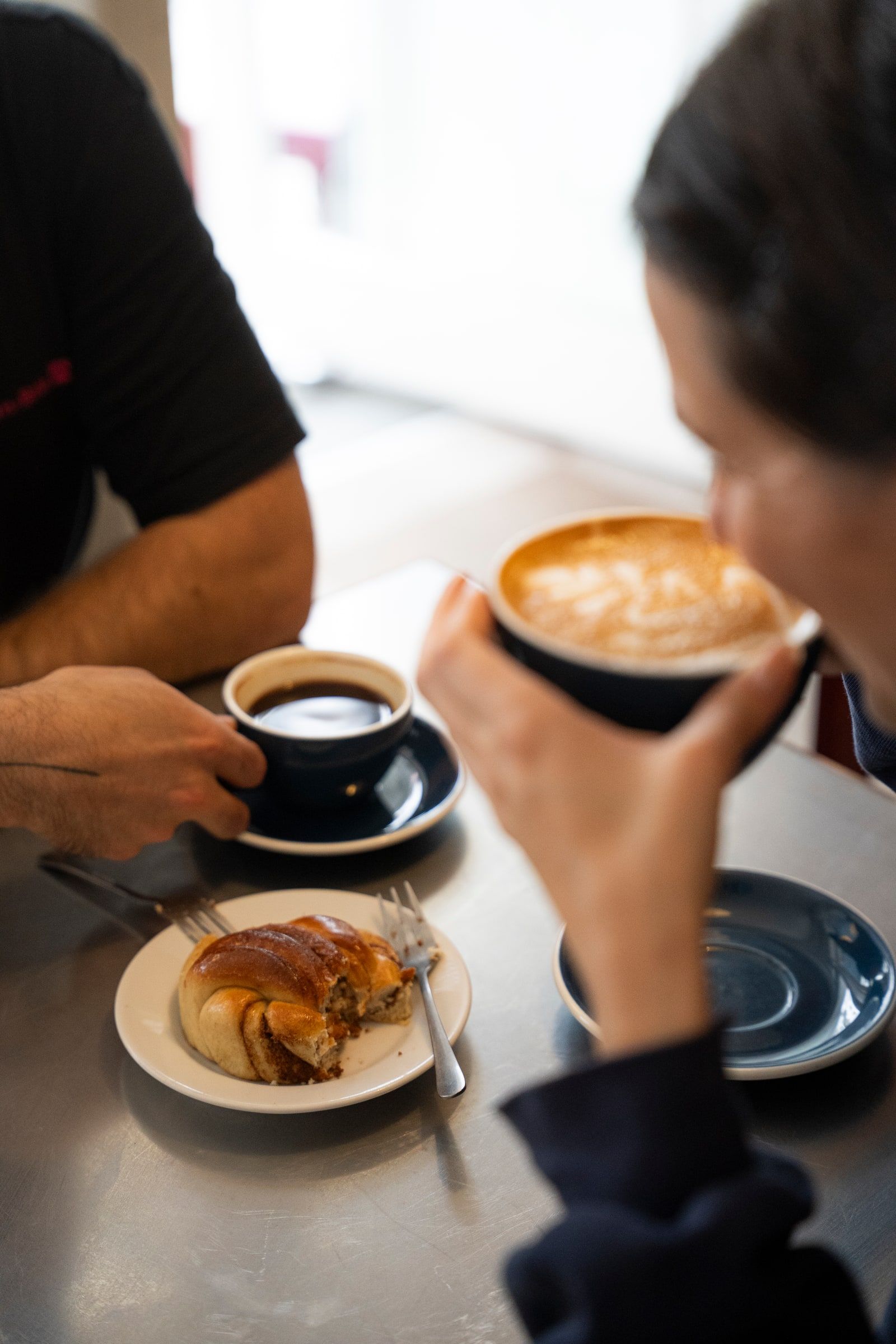 Two people at a table with coffee and a pastry